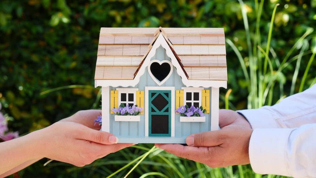 illustration assurance logement petite maison en bois dans les mains des deux personnes