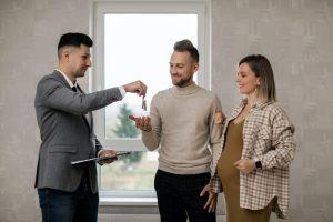 mandataire immobilier offrant au jeune couple les clés de leur nouvelle résidence